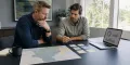 Restoration company owner and marketing strategist comparing two campaign plans beside an unlabeled service territory map